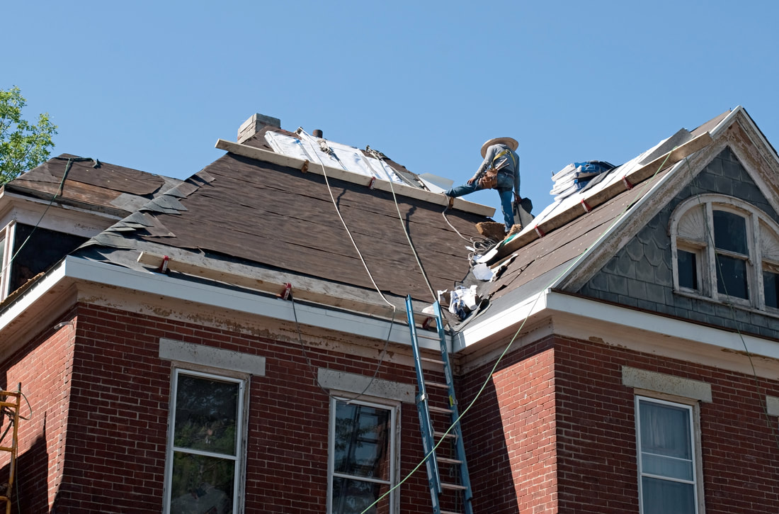 A roofer placing underlayment for a full roof replacement.