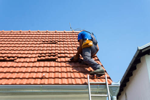 A picture of a roofer replacing and installing tiles in Avondale Arizona.