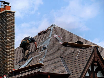 A roofer working down a roof behind a chimmey.