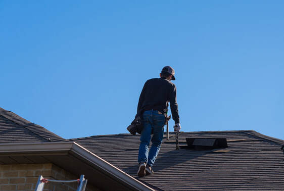 A picture of a roofer holding tools over a roof top.