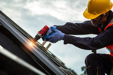 A picture of a roofer nailing down roof tiles over a roof.